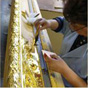 Patience as an expert applies the layer of gold to the frame