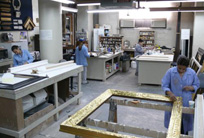 An expert gilder works in the frame restoration studio